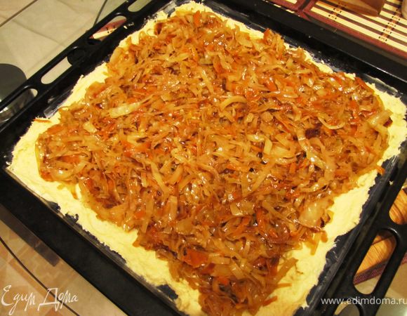 Тесто разделить на две части. На смазанном противне разложить одну часть. Я растягиваю руками прямо на противне. Положить сверху начинку.