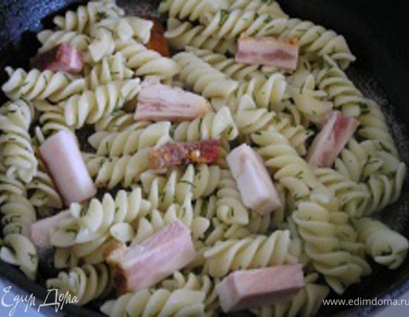 Разогреть сковородку с растительным маслом, выложить макароны и нарезанный кусочками бекон.