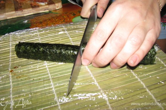 Оставшуюся полоску нори немного смачиваем и склеиваем ролл. После чего придаем ему желаемую форму и смоченным ножом разрезаем пополам.