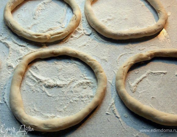 Разделить тесто на 8 равных частей. Раскатать в тонкие длинные жгуты (толщина примерно 1-2 см, тут, скорее, даже не раскатывать, а растягивать нужно, точнее, сочетать два приема), концы соединить и скрепить. Накрыть заготовки слегка влажным полотенцем и оставить на 30 минут.