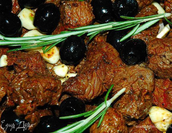 Теперь нам надо очень быстро, но порционно обжарить кусочки нашей говядины на раскаленной сковороде или гриле без масла, буквально 2-3 минуты. Обжаренное мясо выкладываем в наш сотейник поверх овощей. Теперь добавим маслины, рубленый чеснок и веточки свежего розмарина. Перемешивать содержимое никак нельзя! Просто ставим наш сотейник на плиту и вливаем в него бутылку белого сухого вина. Выпариваем вино в течение 15 минут.