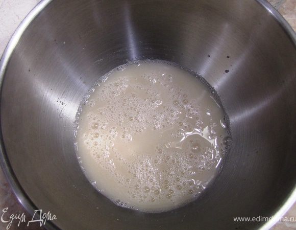 Смешайте воду и дрожжи в большой посуде венчиком или лопаточкой (она должна быть в несколько раз больше, чем объем теста, т.к. и смешивание и расстойка происходит в этой посуде).