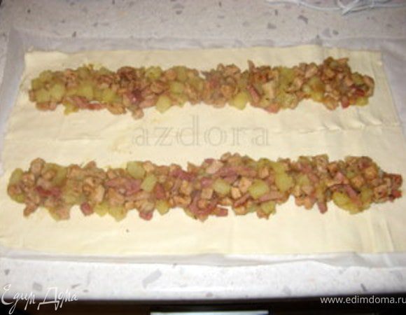 Слоёное тесто не раскатывать, но разрезать вдоль на две части.
Выложить начинку на каждую полоску теста.
