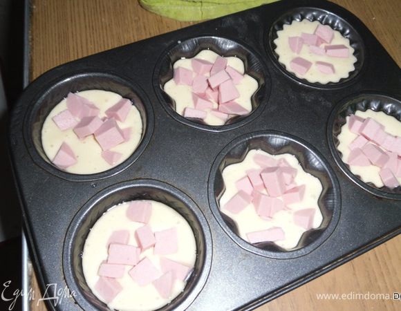 Добавить специи.Все тщательно перемешать.
Формочки смазать маслом, положить ложку теста, колбаску