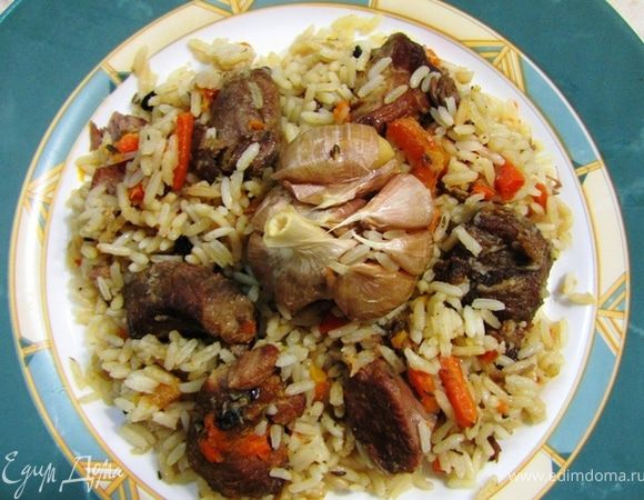 К концу тушения вскипятите пару литров воды.
Налейте в зирвак пол литра кипятка, чтобы несколько снизить температуру. Выровняйте зирвак и засыпьте сверху рисом, чтобы образовалась ровная поверхность.
Положите сверху на рис блюдце или маленькую тарелку. При наливании сверху кипятка тарелка будет равномерно распределять потоки воды, что не позволит рису вымываться под струей кипятка.
Воды надо залить на полтора сантиметра выше края риса. У вас может уйти от полутора до двух литров воды.
Закройте крышкой кастрюлю и сделайте минимальный огонь.
В таком виде плов у вас будет тушиться около часа. Минут через сорок практически вся вода впитается и тарелку можно будет убрать. В центре риса сделайте глубокую ямку, чтобы в нее можно было положить головку чеснока. Положите головку и присыпьте сверху рисом.
В конце готовки для проверки готовности ударьте шумовкой по рису. Если звук будет глухой - значит рис готов.
Выключите огонь.
Сделайте несколько отверстий в рисе деревянной палочкой. Разровняйте сверху рис, накройте крышкой и оставьте плов на 15-20 минут, чтобы он дошел до кондиции, не забыв накрыть крышкой.
По истечении 20 минут перемешайте рис с зирваком (мясом).
Подавайте вместе с пловом тушеные зубчики чеснока.