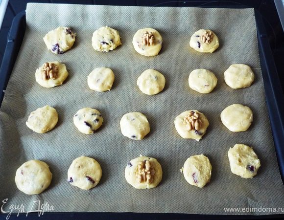 Руки смочить водой, из теста формировать шарики размером с грецкий орех, немного приплюснуть и выложить с небольшим отступом на противень, покрытый бумагой для запекания. Оставшиеся орехи 
выложить сверху на печенье. 