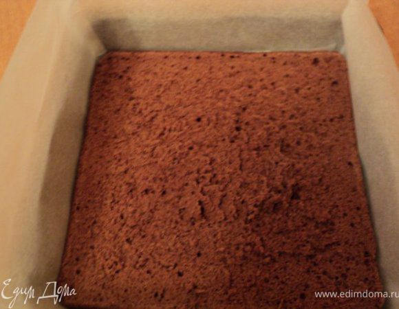 Форму вновь застелить бумагой для выпечки. На дно положить один пласт темного бисквита.