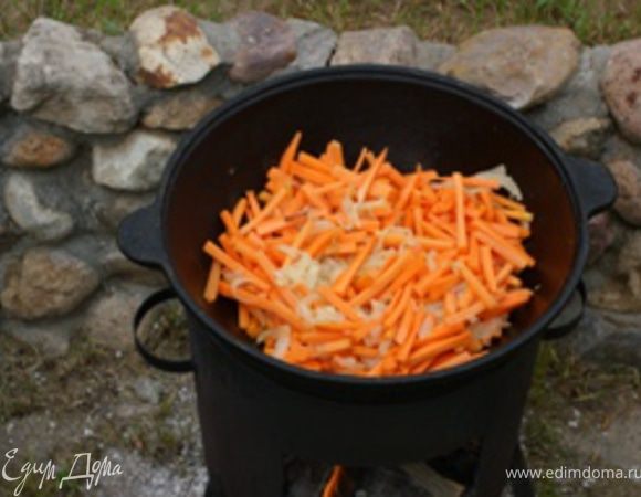 Морковь помыть, очистить и порезать брусочками (толщина около 5 мм, длина около 5 см - т.е. как для плова) и добавить к луку. Продолжать тушить 15-20 минут. Огонь средний.