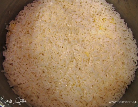 Намажьте дно широкой кастрюли маслом. Выложите картофелем дно кастрюли так, чтобы максимально заполнить поверхность.
Половину риса смешайте с половиной жидкого сливочного масла и выложите поверх картофеля.