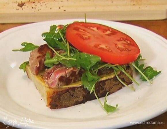 Смазать один кусок хлеба горчицей, выложить нарезанное мясо, сверху руколу и кружок помидора.