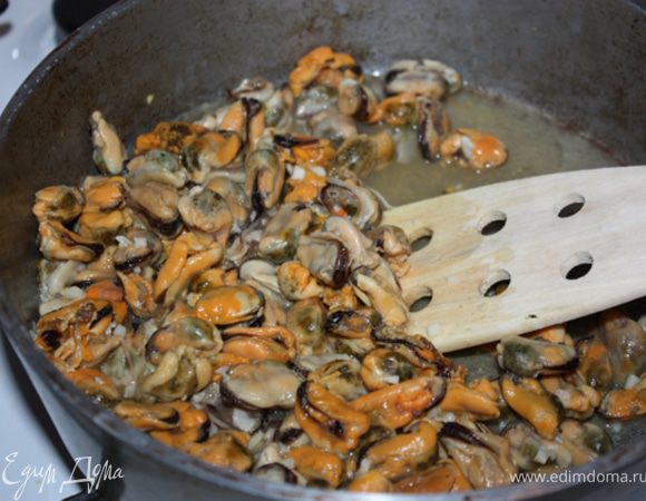 Прогреть оливковое масло на сковороде. Добавить туда мелко порезанный чеснок и мидии. Накрыть крышкой. Тушить где-то 5 мин.