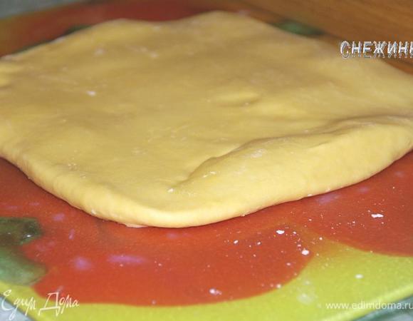 Через 30 минут достаньте тесто из холодильника, положите на рабочую поверхность таким же образом, каким оно лежало на тарелке и раскатайте скалкой так, чтобы можно было вновь свернуть конвертом.