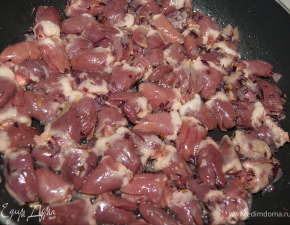 В сковороду с луком положите подготовленные сердечки, перемешайте, накройте крышкой.