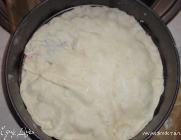 Раскатываем другую часть теста и выкладываем сверху вишен, края немножко прижимаем к первому коржу.