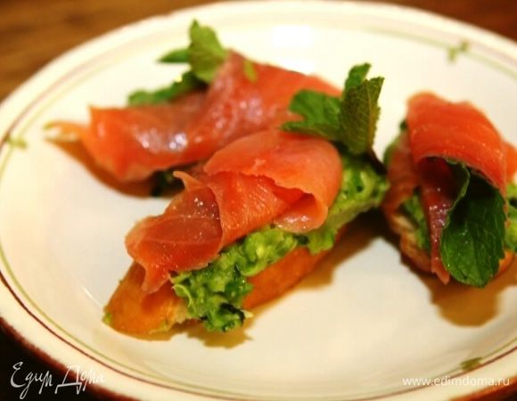 Выложить на гренки гороховую массу, сверху уложить семгу, украсить оставшейся мятой. 