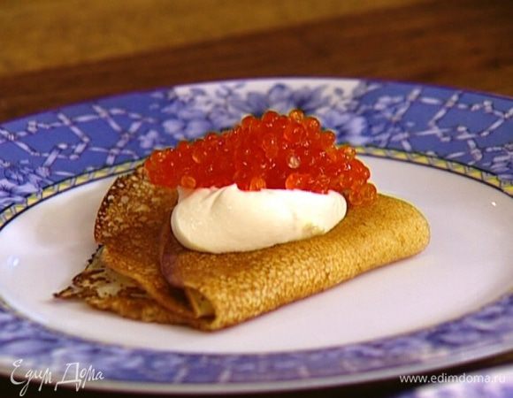 Каждый блин сложить пополам, затем еще раз сложить, чтобы получился треугольник, положить на него немного сметаны, а сверху — красную икру.