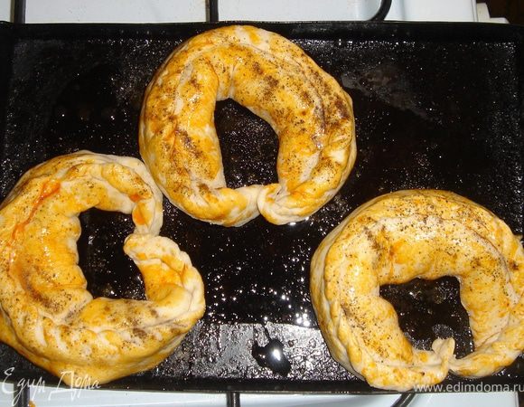 Тесто раскатываем тонким пластом , примерно 10Х20см. В центр по всей длине кладём грибную начинку, по ней сверху раскладываем пластинки плавленного сыра.
Тщательно защипываем тесто, сворачиваем крендельком.