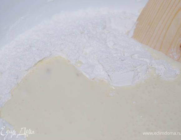 Влить эту смесь в муку и перемешать деревянной лопаткой.