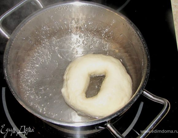 Сложите багельсы на посыпанную мукой поверхность и подержите их там минут 10.
Вскипятите воду в большой кастрюле на среднем огне.
Складывайте багельсы в кипящую воду секунд на 15, но не больше, иначе они могут лопнуть.