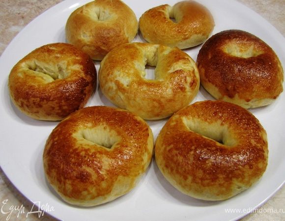 Уложите багельсы на смазанный маслом противень.
Добавьте в желток чайную ложку воды и размешайте. Так проще будет намазывать багельсы.
Намажьте кисточкой желток сверху багельсов.
Выпекайте багельсы в духовке 20 минут, предварительно разогретой до 200 градусов, пока они не зарумянятся. Остудите их на решетке, чтобы багельсы получились особенно вкусными и сбалансированными.