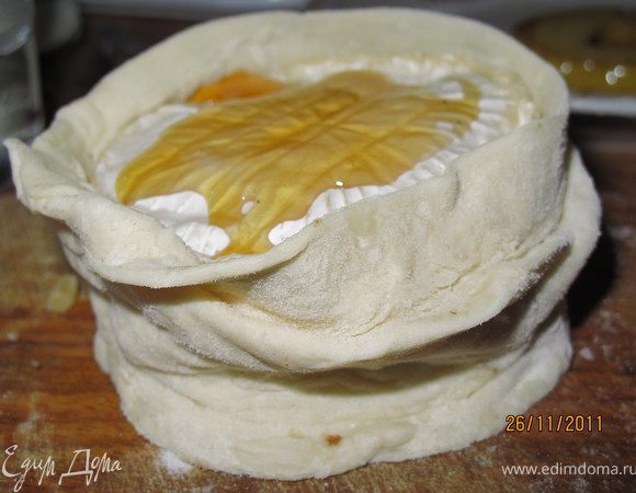 Сверху накрываем сыром с плесенью, обмазываем его мёдом. Оборачиваем наш десерт тестом, края смазываем водой и залепляем.