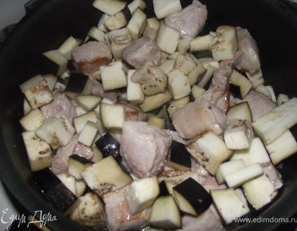 Нарезаем мясо средними кубиками, обжариваем в оливковом масле до полуготовности. Нарезаем баклажаны кубиками и выкладываем к мясу, убавляем огонь до минимума.