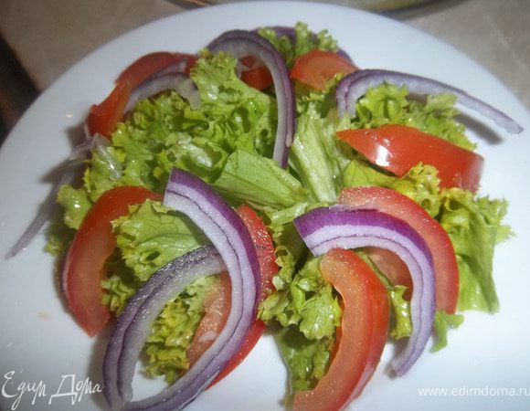 На тарелку положить разделенные на кусочки листья салата, нарезанные дольками помидоры, порезанный дольками лук.





