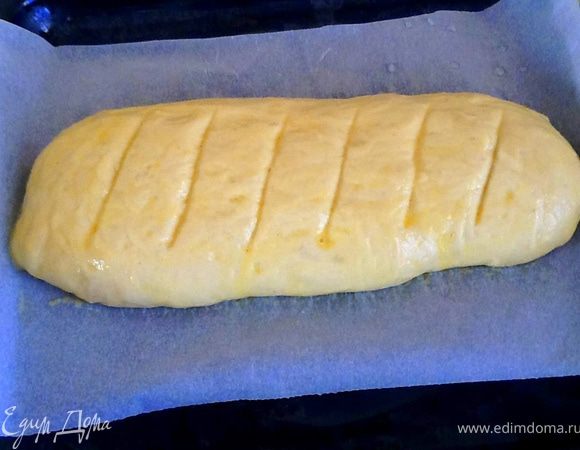 Сделать надрезы, смазать яйцом и по желанию посыпать кунжутом. Выпекать в духовке при 200 °С 30–35 минут до золотистой корочки.