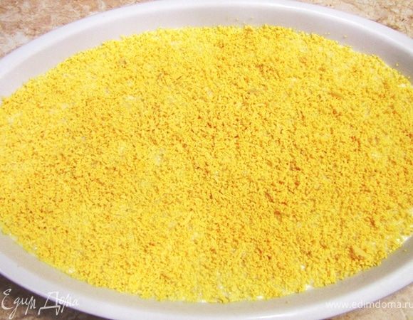 Натрите желтки на мелкой терке. Я натирал непосредственно в блюдо и потом кулинарной кисточкой разровнял. Поставьте в холодильник как минимум на час. Не забудьте накрыть пленкой, иначе салат впитает в себя другие запахи.