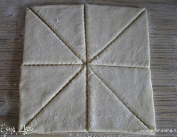 Разморозить слоеное тесто, присыпать мукой с двух сторон, нарезать на порционные треугольники.