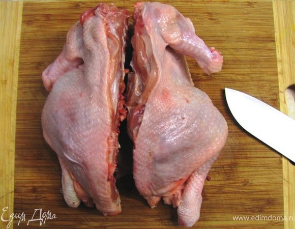 Промойте и обсушите курицу кухонным полотенцем. Положите курицу на разделочную доску грудкой вниз. Срежьте лишние кости с крыльев, как показано на фотографии. Разрежте курицу вдоль позвоночника.