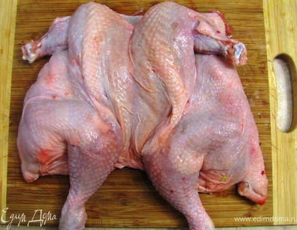 Переверните курицу и постарайтесь ее вывернуть, чтобы она стала "плоской". Стукните по ней кулаком, чтобы косточки сломались и она полностью легла на доску.