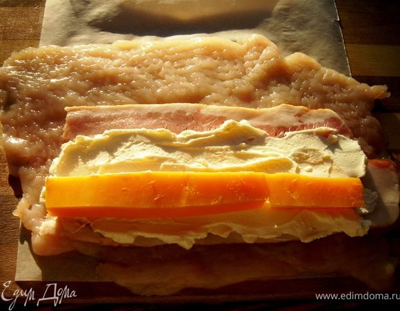 Для второй начинки на куриную грудку выложить ломтик сырокопчёного бекона,на него намазать творожный сыр.Для пикантности в творожный сыр можно добавить чеснок,укроп,мяту или тархун.На творожный сыр выложить ломтики чеддера или другого пикантного сыра.С помощью пергамента свернуть рулет и хорошо завернуть края вовнутрь.