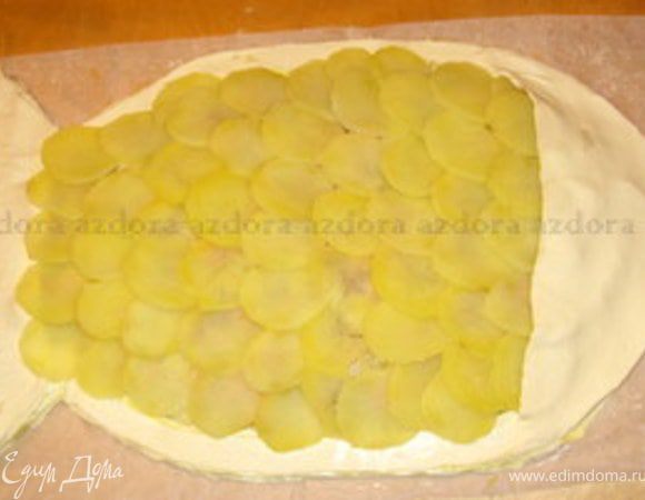 Из ломтиков картофеля сделать чешую.Добавить  голову и хвост рыбки. Сделать глаз из маслины.  Смазать часть рыбки из слоёного теста желтком, который останется отяйца, а картофель оросить оливковым маслом.Чтобы он лучше подрумянился, присыпать его тёртым пармиджано. Запекать при 180° около 30 минут.Через 30 минут покрошить сливочное масло на картофель и запекать ещё минут10.