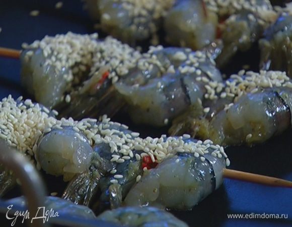 Нанизать креветки на шпажки, уложить в глубокий противень на некотором расстоянии друг от друга и присыпать кунжутом.