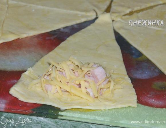 Теперь формируем круассаны с ветчиной и сыром. Раскатываем второй круг теста, делим на 8 треугольничков. На край треугольничка кладем вначале ветчину, сверху сыр и сворачиваем. Укладываем на противень, смазываем яйцом и – в духовку.