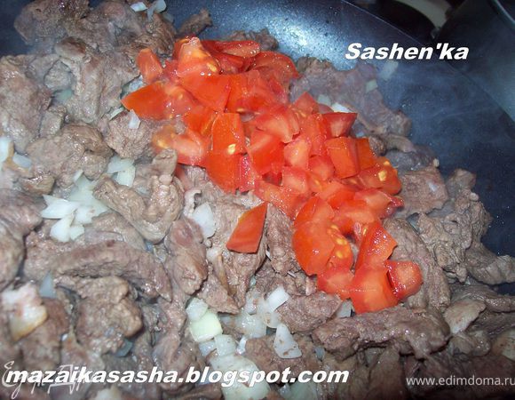 Далее добавляем к бекону мясо и обжариваем. Лук режем кубиком и отправляем к мясу. Обжариваем до золотистого цвета. Добавляем нарезанный не мелким кубиком помидор. Обжариваем 5 минут.