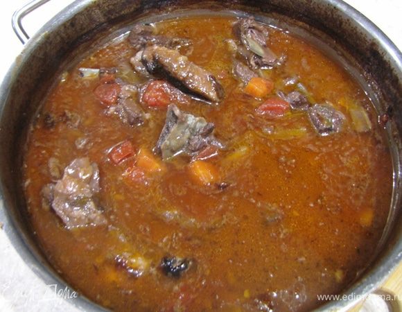 Накройте крышкой и на огне доведите до кипения.
Разогрейте духовку до 180 градусов по Цельсию.
Когда рагу закипит - поставьте кастрюлю в духовку и запекайте в течение двух с половиной или трех часов.
За пол часа до окончания приготовления снимите с кастрюли крышку.

Сверху рагу образовалось немного жира. Я его вычерпал с помощью ложки уже когда достал кастрюлю из духовки. Не бойтесь зачерпнуть часть соуса, более важно как можно более тщательно убрать жир.

Ну вот рагу и готово.