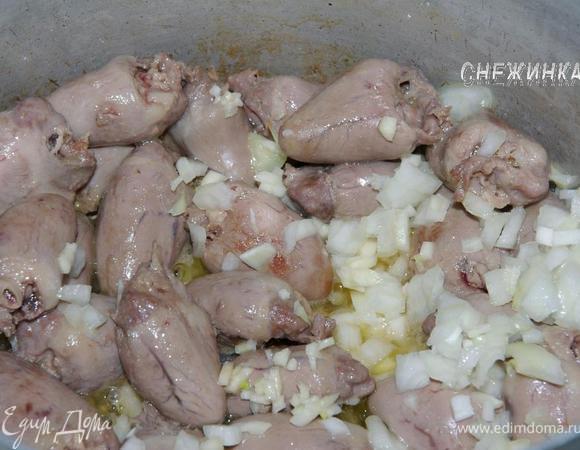 Луковицу очистить, порезать маленькими кубиками. Чеснок почистить и также мелко порезать. Добавляем их к сердечкам и обжариваем дальше до мягкости.