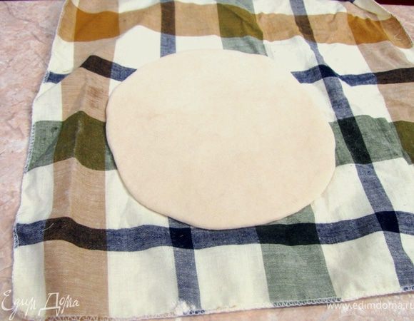 Скалкой раскатайте тесто в круглую форму, толщиной не более 5 миллиметров.
Положите питу на посыпанную мукой поверхность или полотенце и накройте ее другим полотенцем.