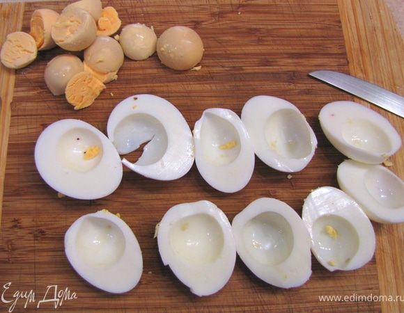 Разрежьте яйца пополам и вытащите желтки. Их можно будет просто раскрошить в бульон.
Нарежьте белки кубиками размером с горошину.
