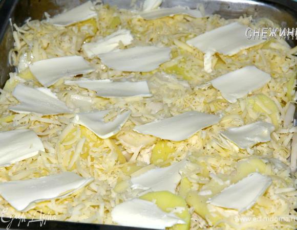 Сверху посыпаем оставшимся натертым сыром. На поверхности равномерно раскладываем кусочки сливочного масла. 