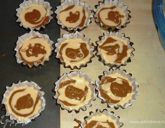 Во внутрь каждого бисквитика вдавливаем слегка по кусочку шоколада. Сверху заливаем ещё чуть-чуть теста.