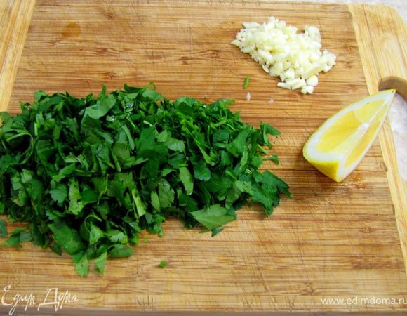 Налейте в сковороду вино и деглассируйте мясные остатки (потрите дно сковороды лопаткой, чтобы мясные остатки отошли от нее и растворились в вине.
Налейте туда же бульон.
Мелко порубите чеснок и петрушку. Я добавил еще кинзу, но это по вкусу. Отрежьте от лимона дольку с кожурой (лучше поперек лимона)