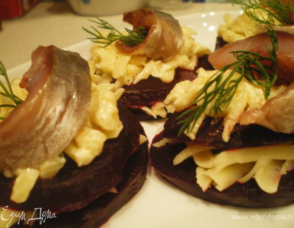 Свеклу нарезать кружочками. Сыр натереть на крупной тёрке и смешать с майонезом. Сельдь нарезать на полоски. Выложить слоями: кружок свеклы - сыр - кружок свеклы - сыр - сельдь. Украсить зеленью.