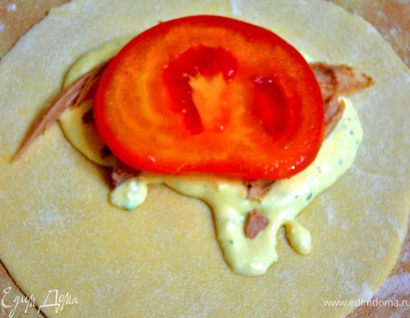 Теперь берем один круг,на присыпанной мукой поверхности,слегка расскатываем еще.Положить на одну половину круга творожную массу(примерно 1 ст.л.).Поверх нее филе,помидор. 