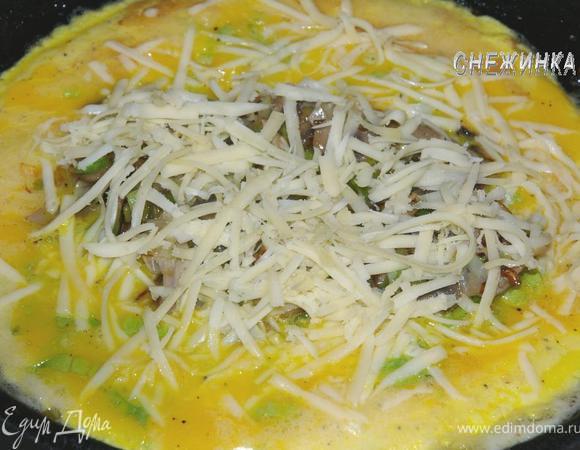 Когда серединка омлета будет еще жидковата, выкладываем сверху начинку и посыпаем сыром.