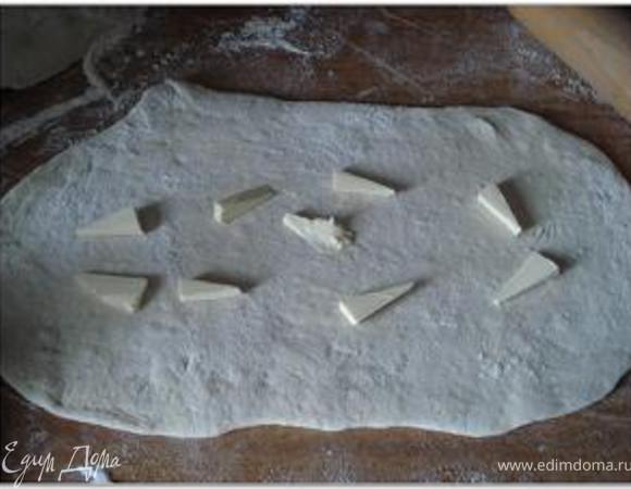 Приготовленное тесто выложить на доску, посыпать мукой, разделить на две части и раскатать полосы вдоль.