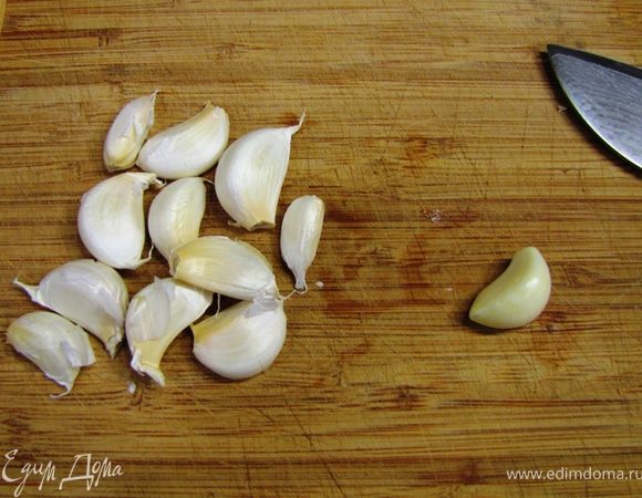 Возьмите чеснок и разберите его на зубчики. Надавите на зубчик, чтобы кожица лопнула. Так легче будет снять ее. Срежьте попку и снимите кожицу.
