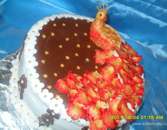 Раскатать мастику в длинный пласт по форме хвоста. Вверху хвост узкий, книзу расширяется. Приклеить хвост к телу птицы водой. Под хвост положить скатанные шарики пищевой пленки (чтобы удерживали форму хвоста). Оставить сохнуть на 1,5-2 часа. Затем начинаем клеить перья на хвост, начинать надо снизу, укладывая немноговнахлест. На фото можно увидеть под перьями как раз белый хвост из мастики, на который крепились перья.